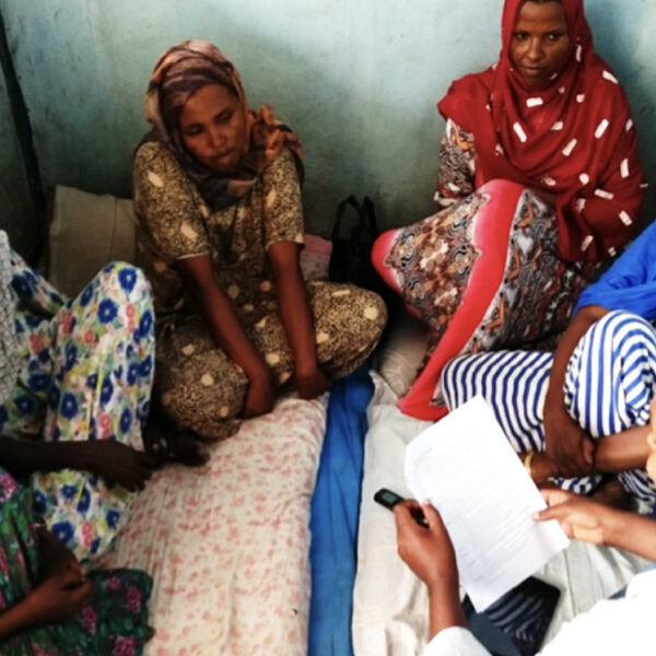 Health extension worker sitting with clients and having a discussion.